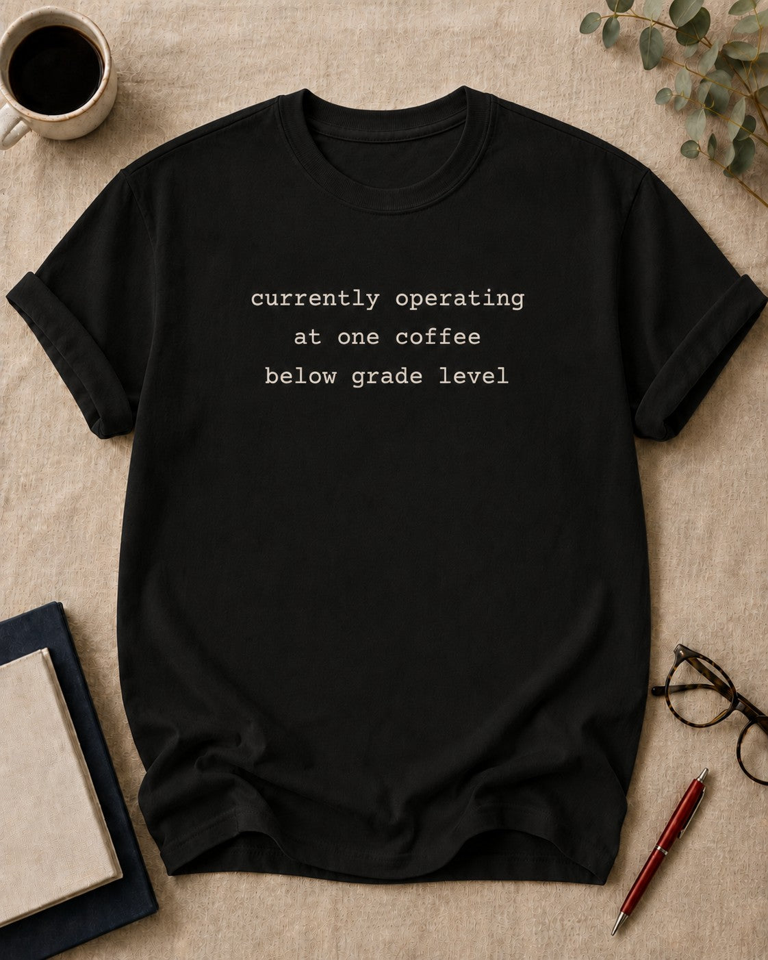 I'm currently operating at one coffee below grade level. teacher t-shirt in Black, flat lay